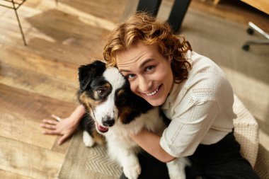 Neşeli bir genç adam sıcak bir ev ortamında köpeğiyle neşeli bir anı paylaşıyor..