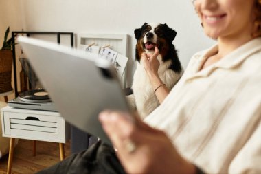 Evde dinlenen genç bir adam köpeğiyle bir tablet üzerinde gezinirken etkileşime girer ve neşe yaratır..