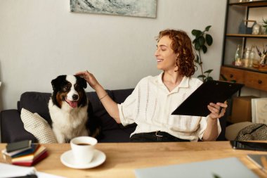 Genç bir adam köpeğini okşarken gülümsüyor, evinde rahat bir ortam yaratıyor..