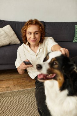 Genç adam yerde rahatlıyor, sıcak bir yuva ortamında dost canlısı köpeğiyle güzel vakit geçiriyor..