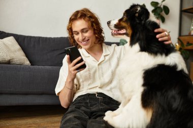 Genç bir adam sıcak oturma odasında köpeğiyle güzel vakit geçirmekten hoşlanır..