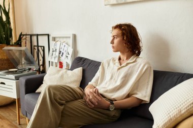 Genç bir adam rahat bir şekilde kanepede oturuyor, şık evinde sakin bir anın tadını çıkarıyor..