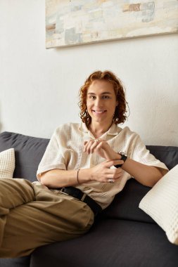 Genç bir adam rahatça evinde uzanıyor, rahatlarken sıcaklık ve cazibe saçıyor..