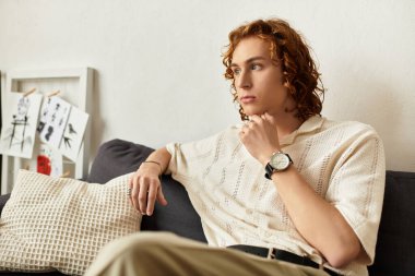 Genç bir adam rahat evinde bir kanepede oturur, düşüncelere dalmış ve derin düşüncelere dalmış..