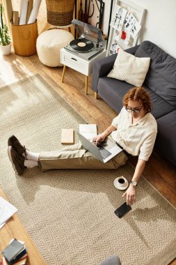 Genç bir adam evinde dinlenmenin keyfini çıkarıyor. Laptopuyla kahveyle çalışıyor..