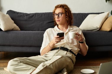 Genç adam evde rahat bir anın tadını çıkarıyor. Telefonunu kontrol ederken kahvesini yudumluyor..