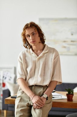 Yakışıklı genç bir adam rahat bir evde duruyor, rahatlamış ve kamerayla meşgul..