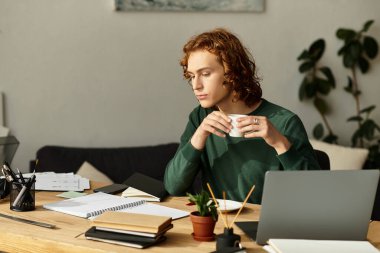 Genç bir adam evdeki masasında oturmuş etrafı notlarla çevrili bir bardaktan yudumluyor..