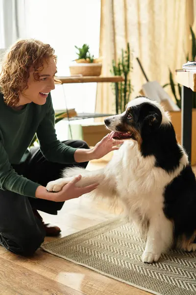 Gülümseyen genç adam, dost canlısı köpeğiyle şakalaşarak sıcak bir ev ortamı yaratıyor..
