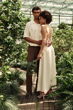 Sevgi dolu bir çift, sakin bir serada yemyeşil bitkilerle çevrili hassas bir anı paylaşır..