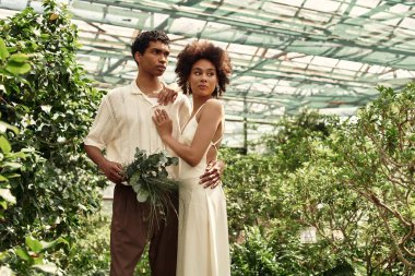 Bir çift, çeşitli bitki ve yeşilliklerle çevrili bir serada hassas bir anı paylaşıyor..