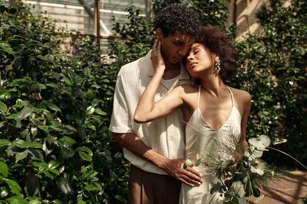 Huzurlu bir serada, yemyeşil bitkiler ve sükunetle çevrili genç bir çift kucaklaşır..