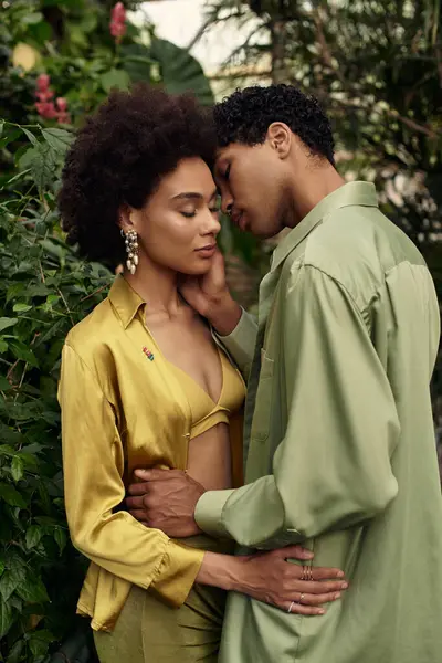 Güzel bir çift, canlı bitkiler ve yapraklarla dolu yemyeşil bir serada sevgiyle kucaklaşır..