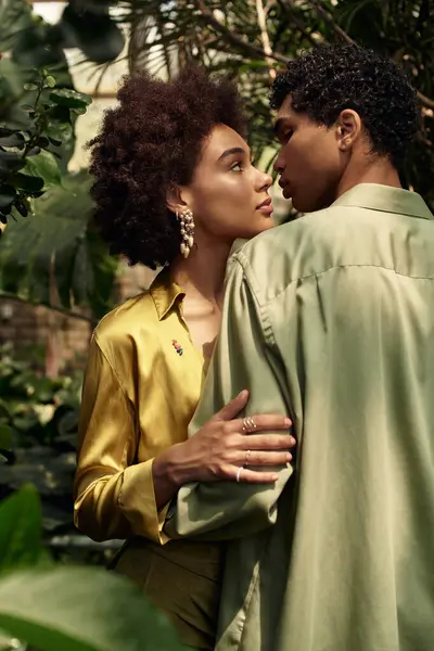 Huzurlu bir serada, genç bir çift, büyüyen yapraklarla çevrili, sevgiyi paylaşıyor..