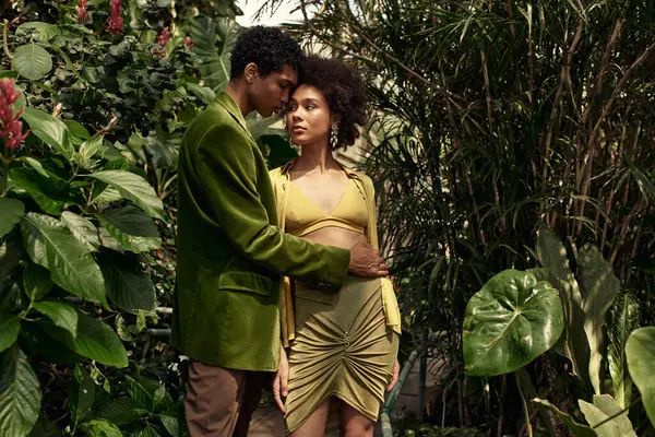 Genç bir erkek ve kadın, canlı bitkilerin arasında sevgi dolu bir şekilde kucaklaşır, onların bağlarını ve neşelerini yakalar..