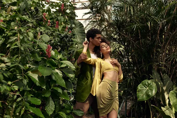 Genç bir çift, canlı bitkilerin arasında şefkatli bir kucaklaşmayı paylaşıyor..