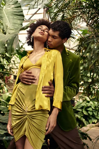 Genç bir çift, yemyeşil bitkiler ve canlı yeşillikler arasında sevgiyle kucaklaşır..