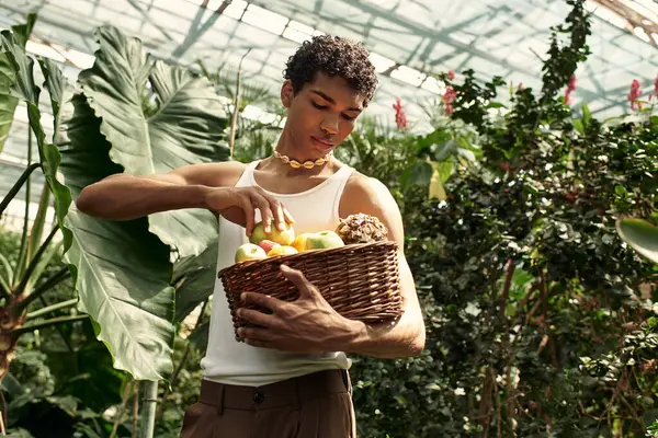 Yeşil ve taze ürünlerle çevrili bir serada aktif olarak poz veren şık genç bir adam..