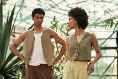 Genç bir çift, canlı bitkiler ve güneş ışığıyla çevrili bir şefkat anını paylaşıyor..