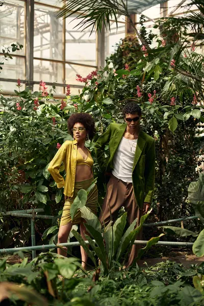 Birbirini seven çiftler, parlak bir sera ortamında egzotik bitkilerle çevrili olarak birbirlerini kucaklarlar..