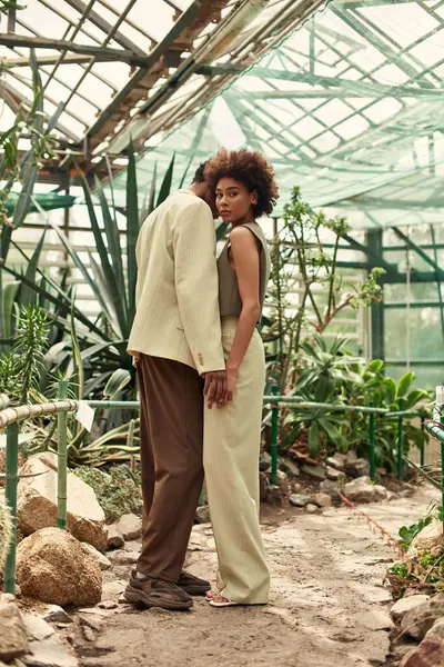 Genç bir çift sıcak bir sera atmosferindeki tropikal bitkiler arasında samimi bir anın tadını çıkarıyor..