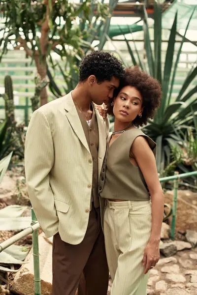 Genç çift, sakin bir serada yemyeşil bitkilerle çevrili samimi bir anı paylaşıyor..