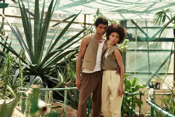 Genç bir çift, canlı bitkilerin arasında sıkıca sarılıp sevgilerini vurguluyor..