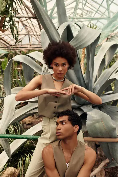 Genç bir çift, dingin sera atmosferindeki canlı bitkilerin arasında hassas bir anı paylaşıyor..