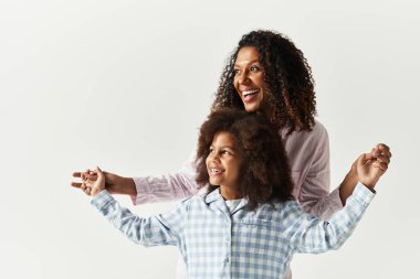 Gülümseyen siyah anne ve kız pijamalarıyla el ele tutuşuyorlar..