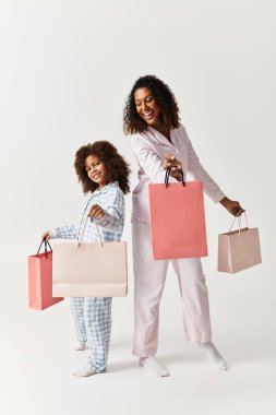 Siyah anne ve kızı aynı pijamalar içinde, alışveriş torbaları, stüdyo.