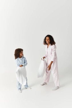 Pijama giymiş anne ve kız stüdyoda şakacı bir yastık savaşı yapıyorlar..