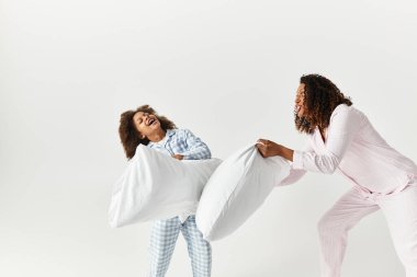 Siyah anne ve kızı bir stüdyoda şakacı bir yastık kavgası yapıyorlar..