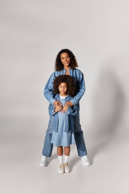 Zenci anne ve kızı kot pantolon içinde bir stüdyoda sarılıyorlar..