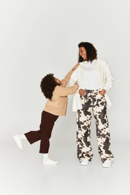 Gri bir geçmişi olan şık bir stüdyoda, bir anne ve kızı birlikte şık kıyafetler giyiyorlar..