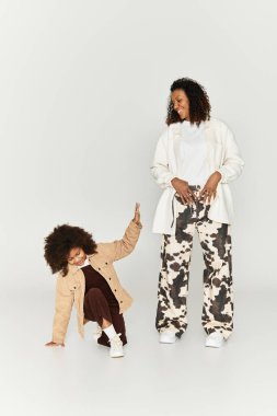 Afrika kökenli Amerikalı anne ve kız moda kıyafetlerle, gösteriş tarzıyla neşeli bir anı paylaşıyorlar..