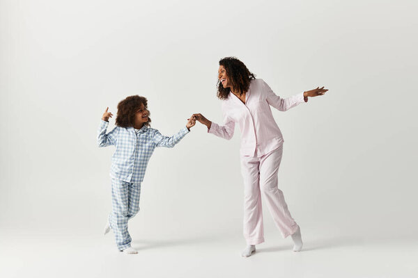Black mother and daughter dancing in cute matching PJs.