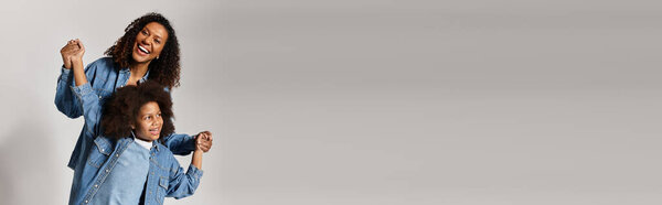 Smiling Black mom and daughter in denim clothes, banner