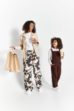 Anne ve kızı şık bir stüdyo ortamında aynı moda kıyafetleri giyerken gülümsediler..