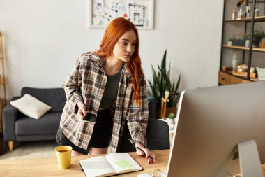 Uzun saçlı genç bir kadın rahat ev ofisinde çalışıyor, odaklanmış ve ilham almış..