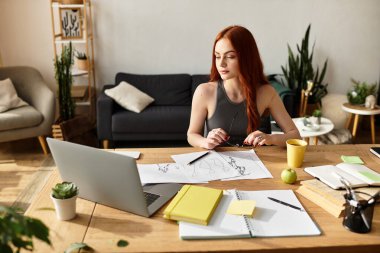 Güzel genç bir kadın ahşap bir masada oturur, çizimlerine ve fikirlerine odaklanır..