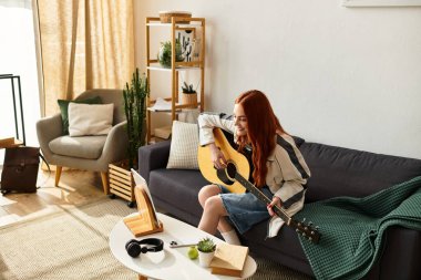 Güzel genç bir kadın, parlak ve güzel dekore edilmiş bir oturma odasında dinlenirken gitar çalar..