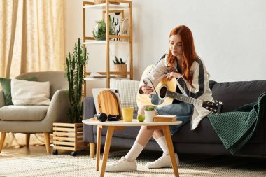 Genç bir kadın gitar çalarken koltukta dinleniyor ve telefonunu parlak bir boşlukta kontrol ediyor..