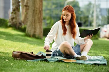 Genç bir kadın yemyeşil bir parkta kahvesini yudumlarken boş zamanlarını kitap okuyarak geçirir..