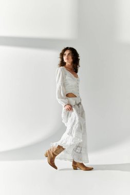 Genç bir kadın, çarpıcı beyaz bir elbise içinde, zarif bir şekilde yürüyor..