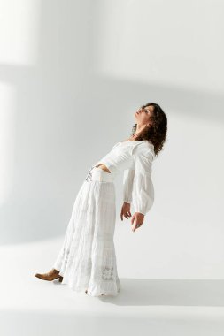 Zarif genç kadın, zarif beyaz bir elbise içinde moda anlayışını sergiliyor, zarafeti kucaklıyor..