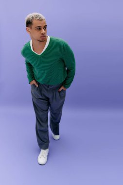 Moda düşkünü, siyah saçlı, genç, Afro-Amerikan bir adam kendine güvenen bir poz veriyor..