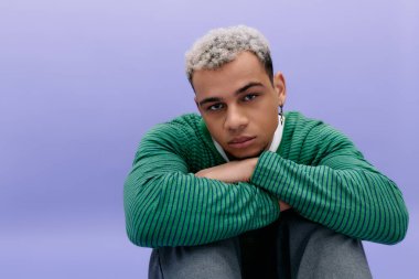 Modayı takip eden genç adam moda anlayışını canlı mor bir fon karşısında boyalı saçlarıyla sergiliyor.