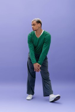 Saçları boyalı genç bir Afrikalı Amerikalı mor bir arka planda moda kıyafetleriyle poz veriyor..