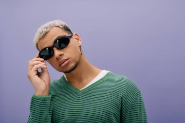 Tarz sahibi genç Afrikalı Amerikalı erkek, saçları boyalı ve modaya uygun bir şekilde poz veriyor..