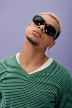 Modaya uygun genç bir adam, kendine has tarzını canlı mor bir arka planda sergiliyor..